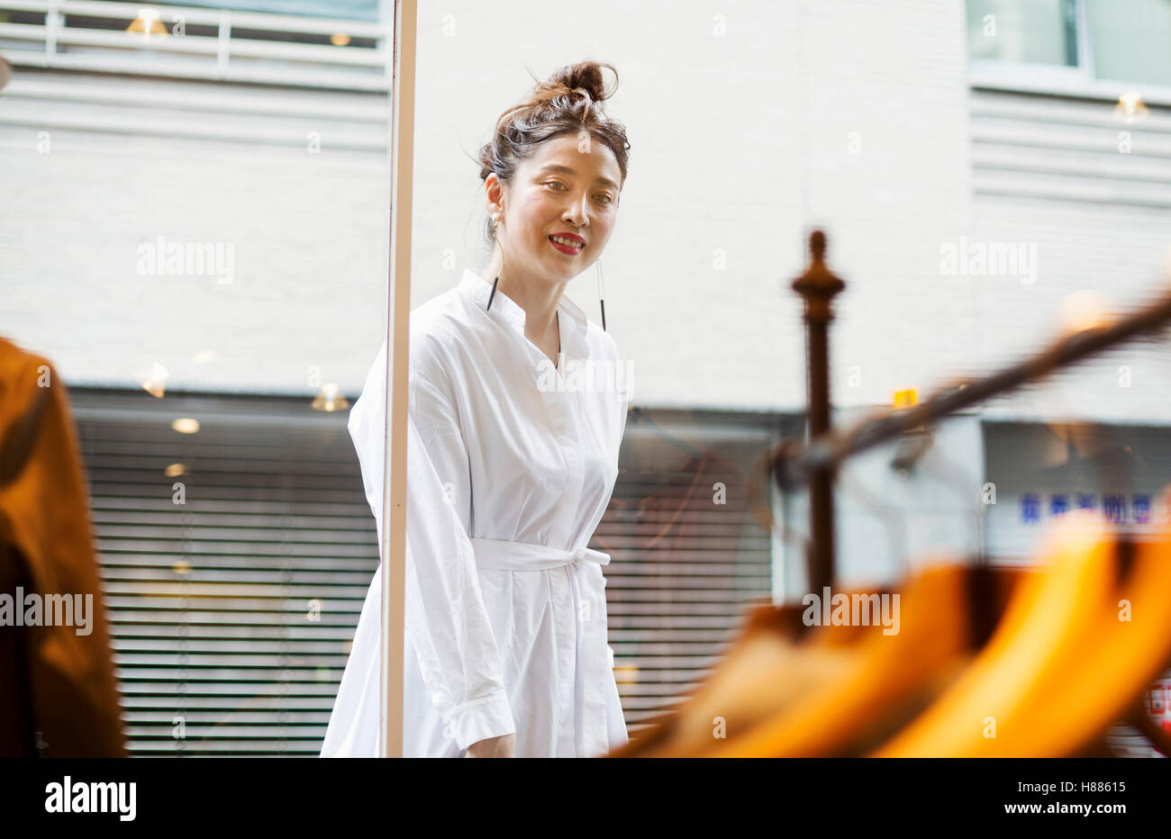 Woman working in a fashion boutique in Tokyo, Japan, looking at window display. Stock Photo