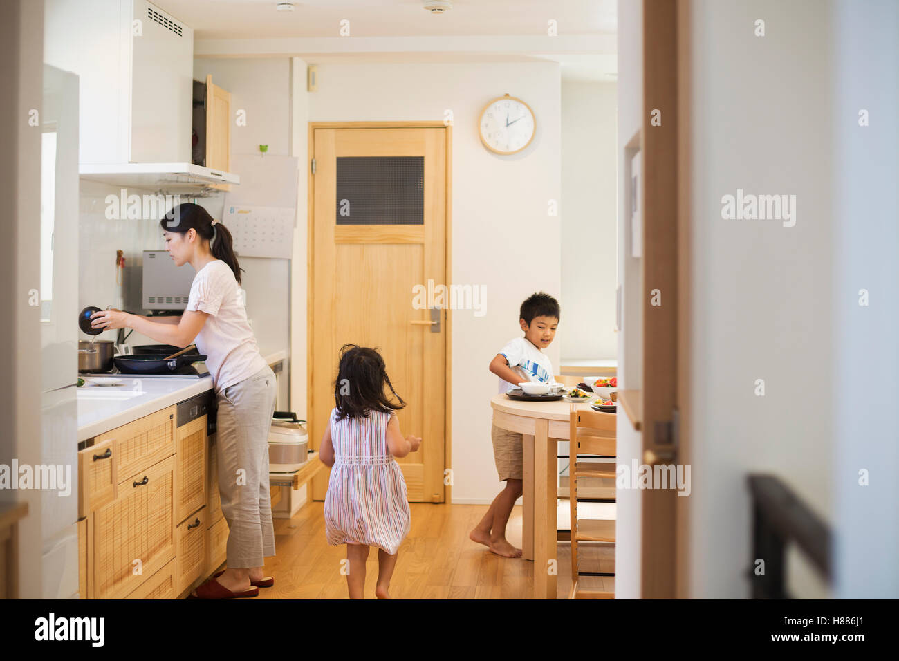 Family home. A woman and two children, a girl and a boy laying the table for a meal. Stock Photo