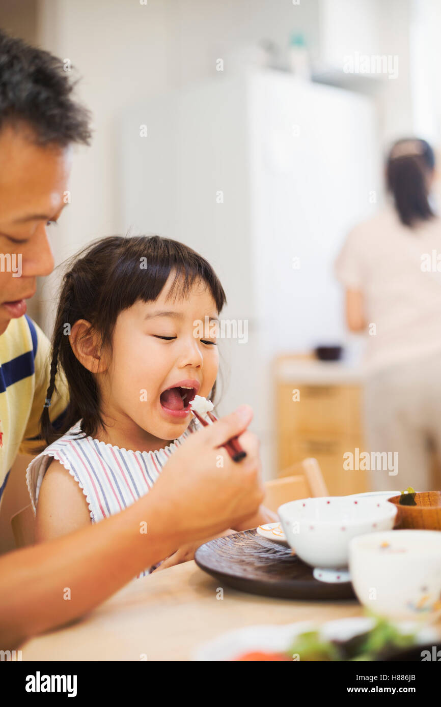 Family home. A man feeding his daughter at a meal. Stock Photo