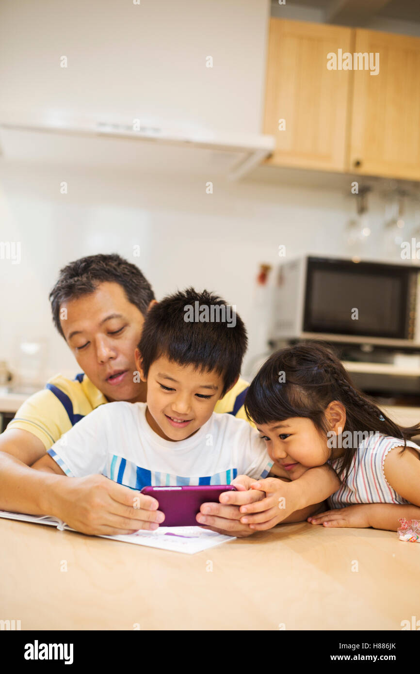 Family home. A man showing his children the smart phone screen Stock Photo