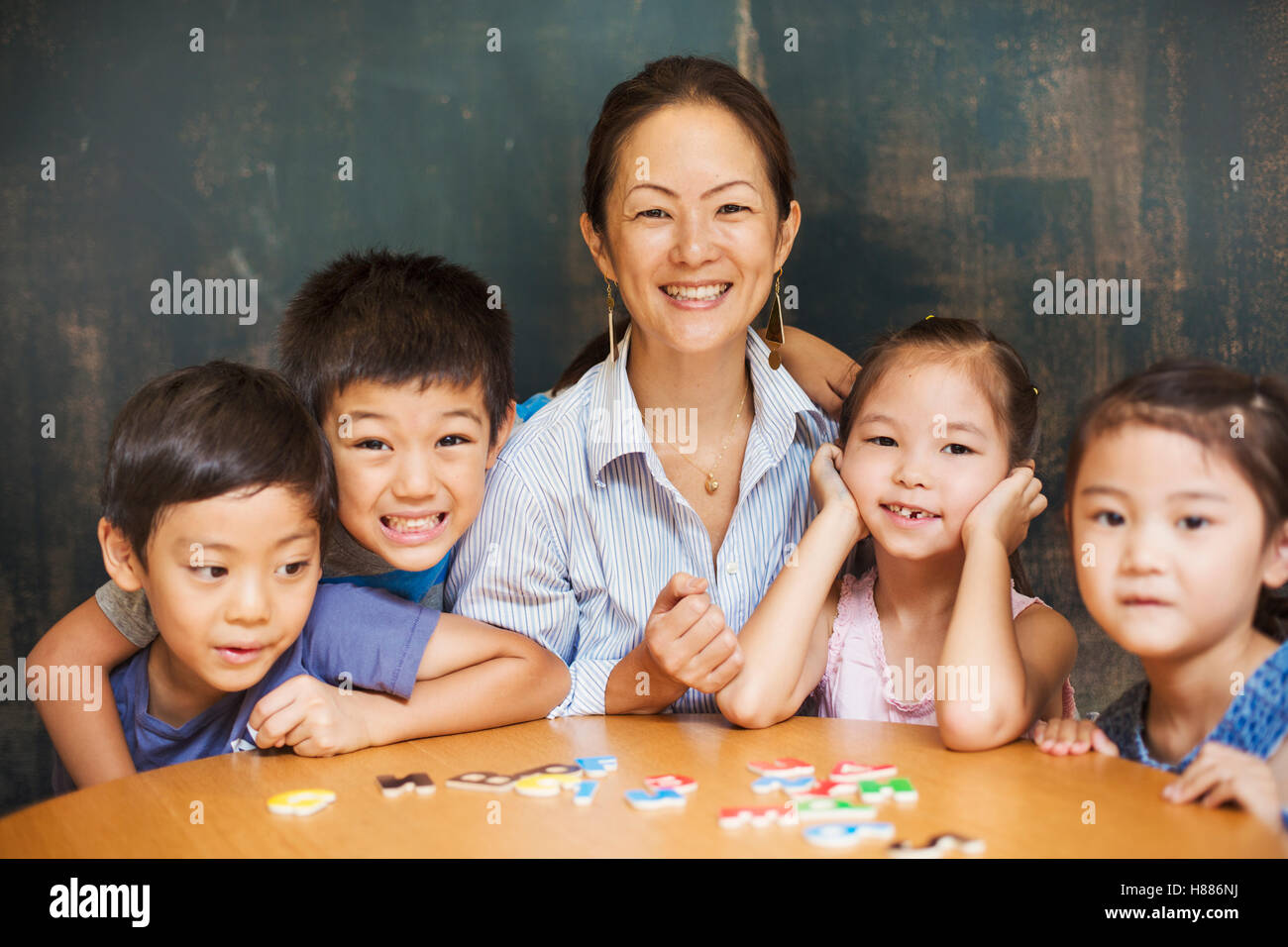 A group of children, boys and girls in a classroom with their teacher. Stock Photo