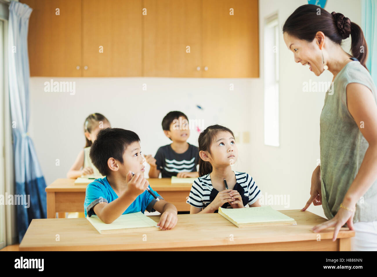 A group of children in a classroom with their female teacher. Stock Photo