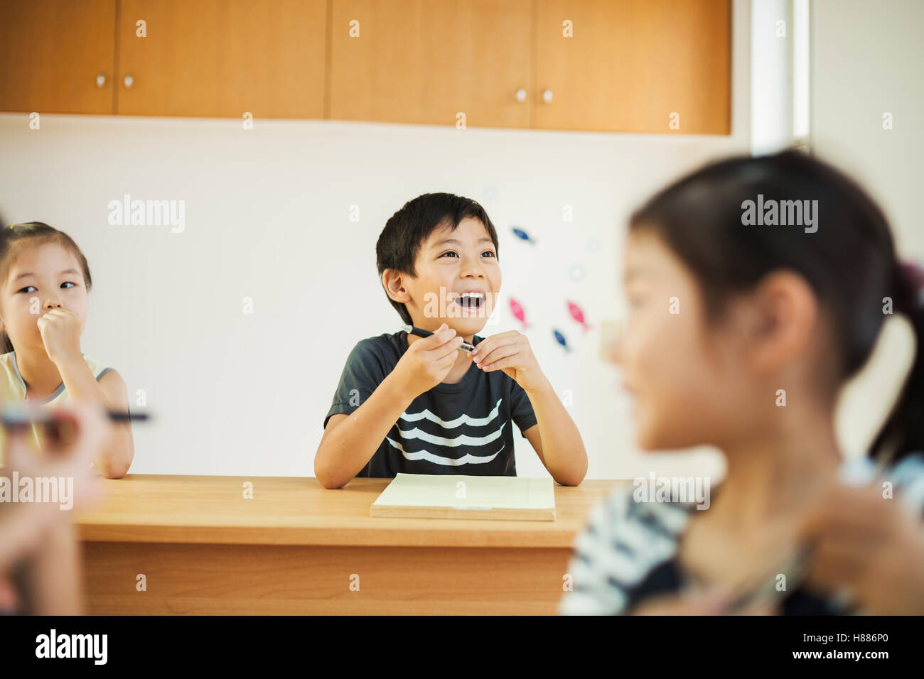 Three children, a boy and two girls in a classroom. Stock Photo
