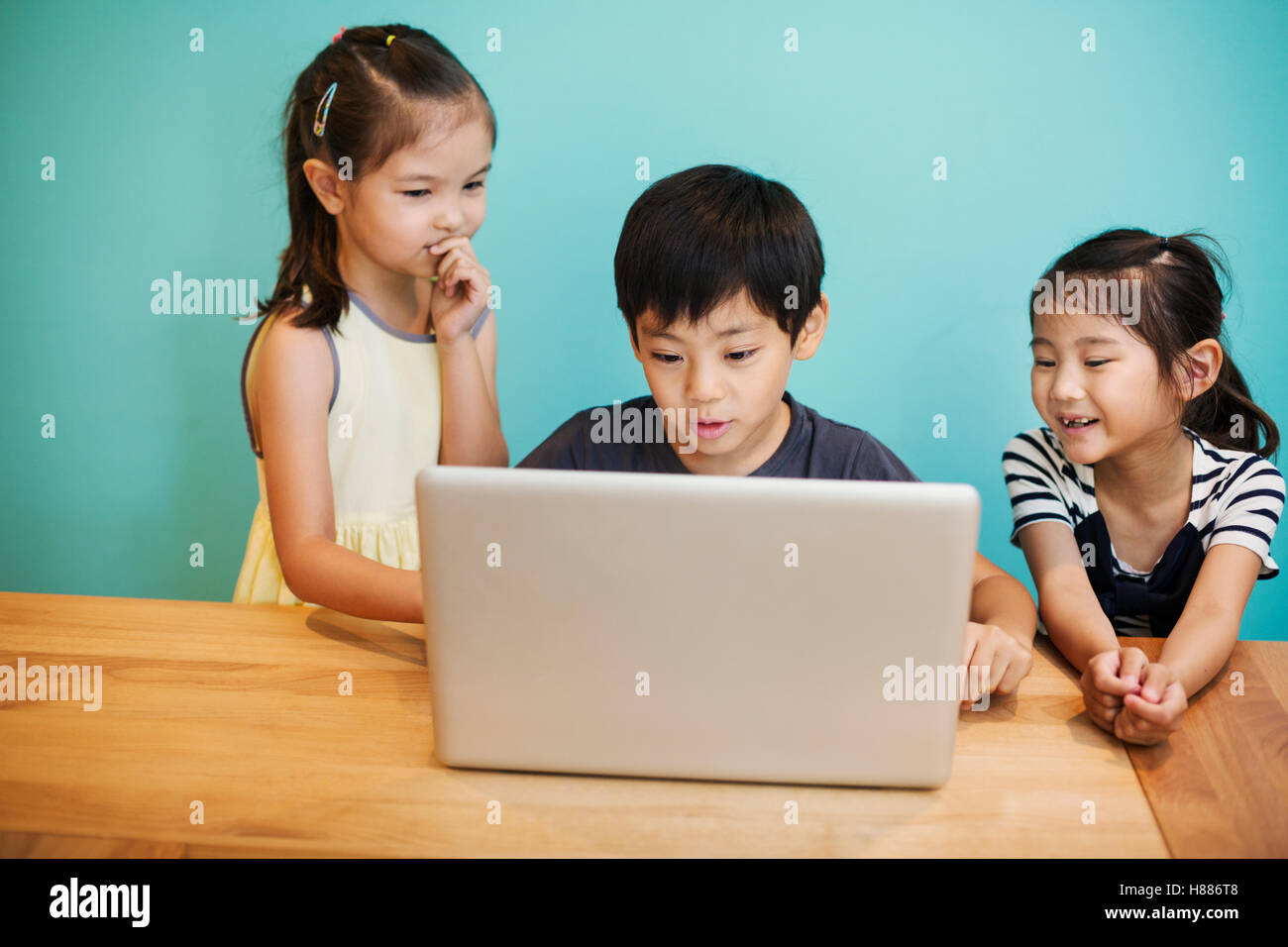A group of children in school, three children sharing a laptop computer. Stock Photo