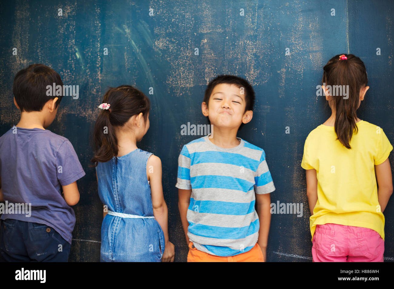 A group of children in school. Four children standing by the blackboard. Stock Photo