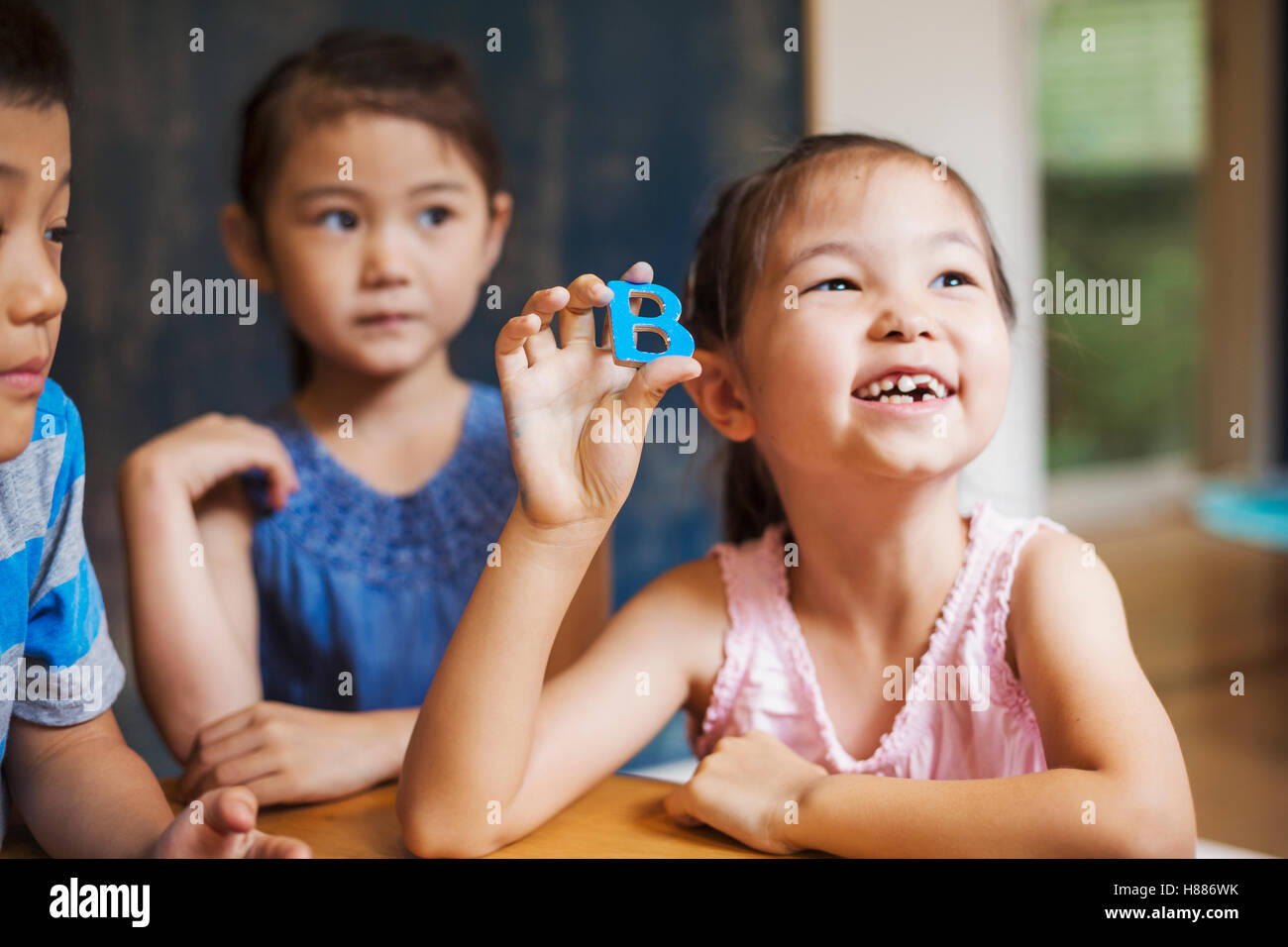 A group of children in school. Two boys and two girls holding up alphabet letters. Stock Photo