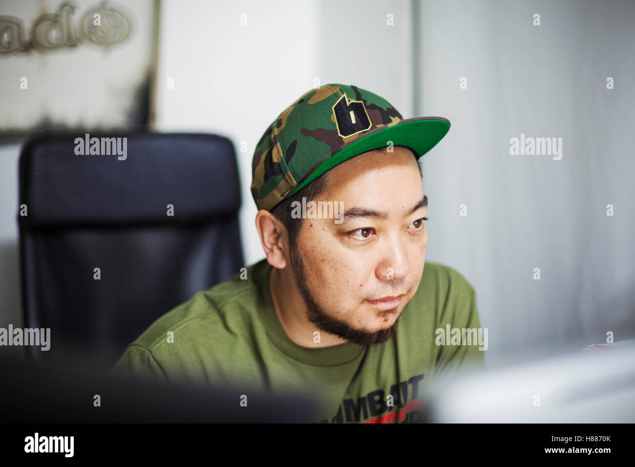Design Studio. A man wearing a baseball cap looking at a screen. Stock Photo