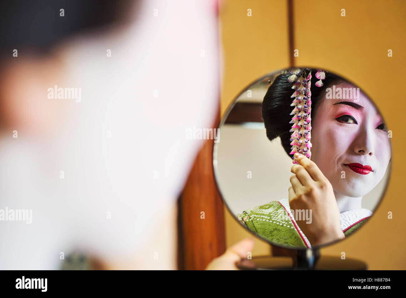 Traditional Geisha Mirror A woman made up in the traditional geisha style, Looking in a hand ...