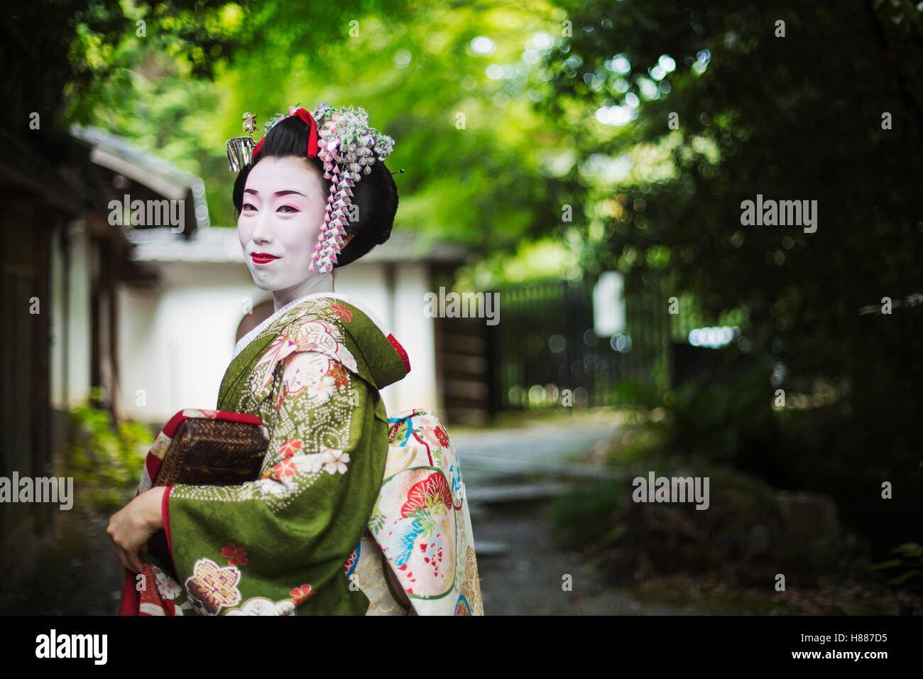A woman dressed in the traditional geisha style, wearing a kimono and obi, side view outdoors. Stock Photo