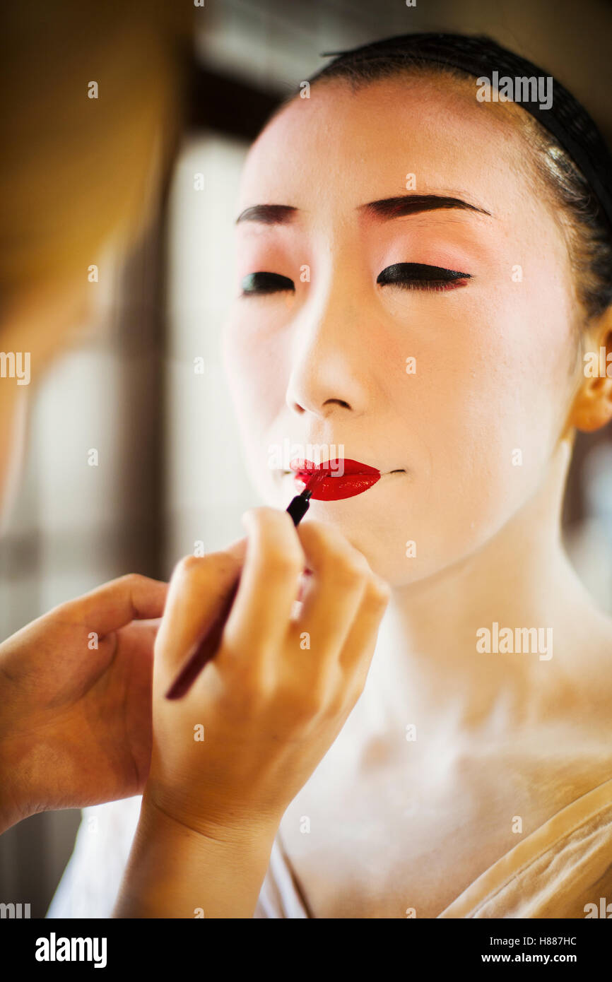 A modern woman creating the traditional geisha vivid red lips by