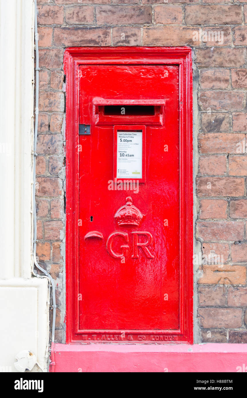 Bright red Royal Mail post box mounted into brick wall Stock Photo