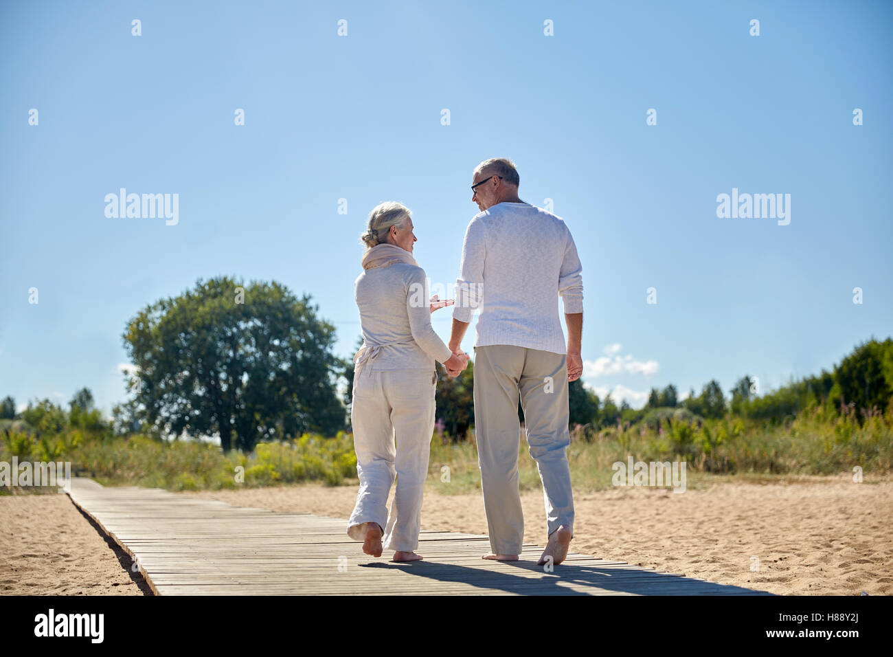 happy senior couple holding hands on summer beach Stock Photo - Alamy