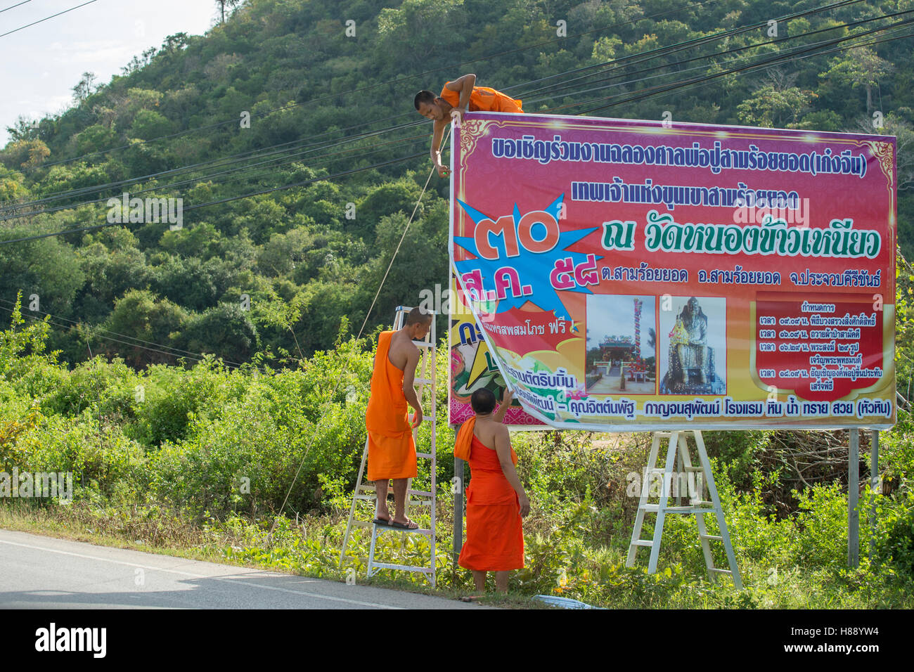 Buddhist monks putting up a sign south of Hua Hin, Thailand Stock Photo