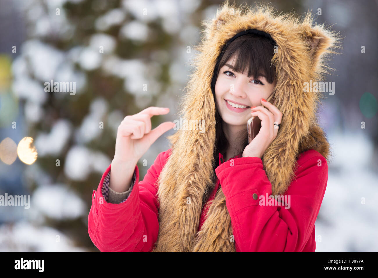 Young woman with smartphone gesturing small amount of something Stock Photo