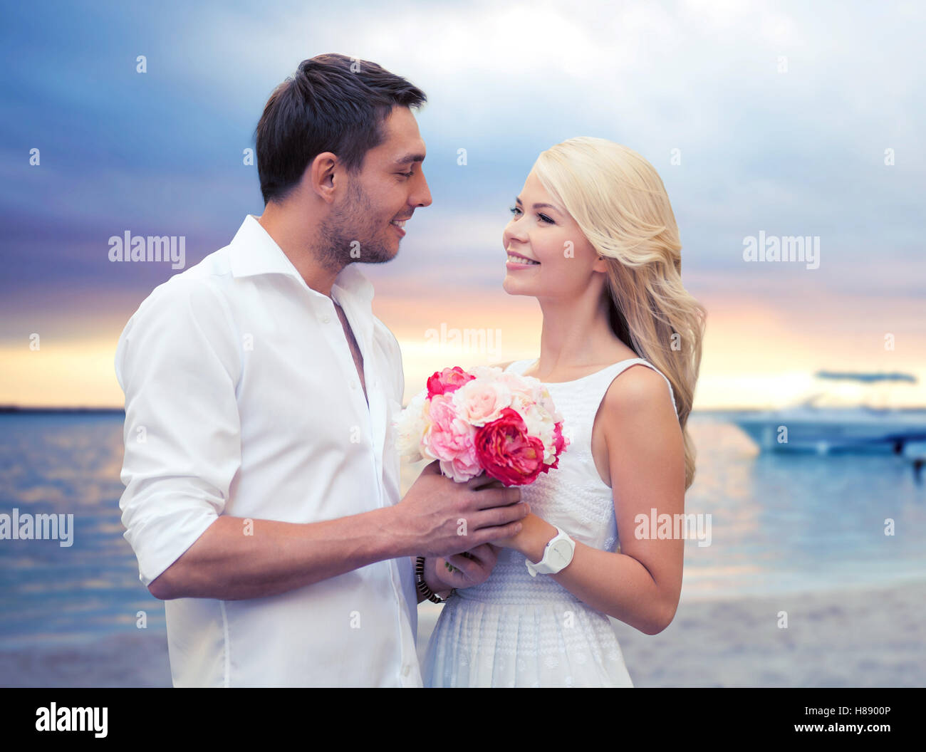 happy couple with flowers over beach background Stock Photo - Alamy