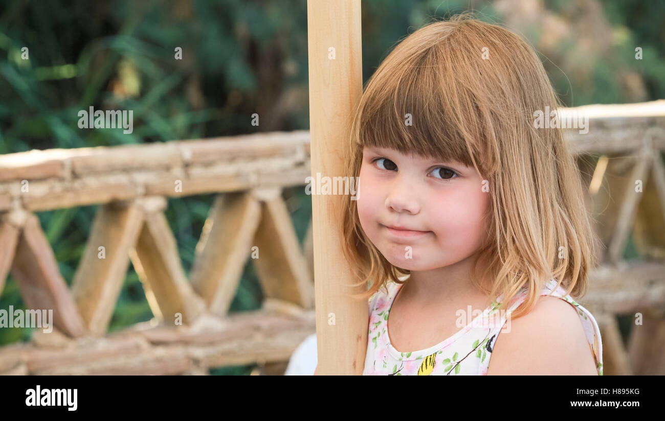 Cute Caucasian little girl standing on balcony, close-up outdoor portrait Stock Photo