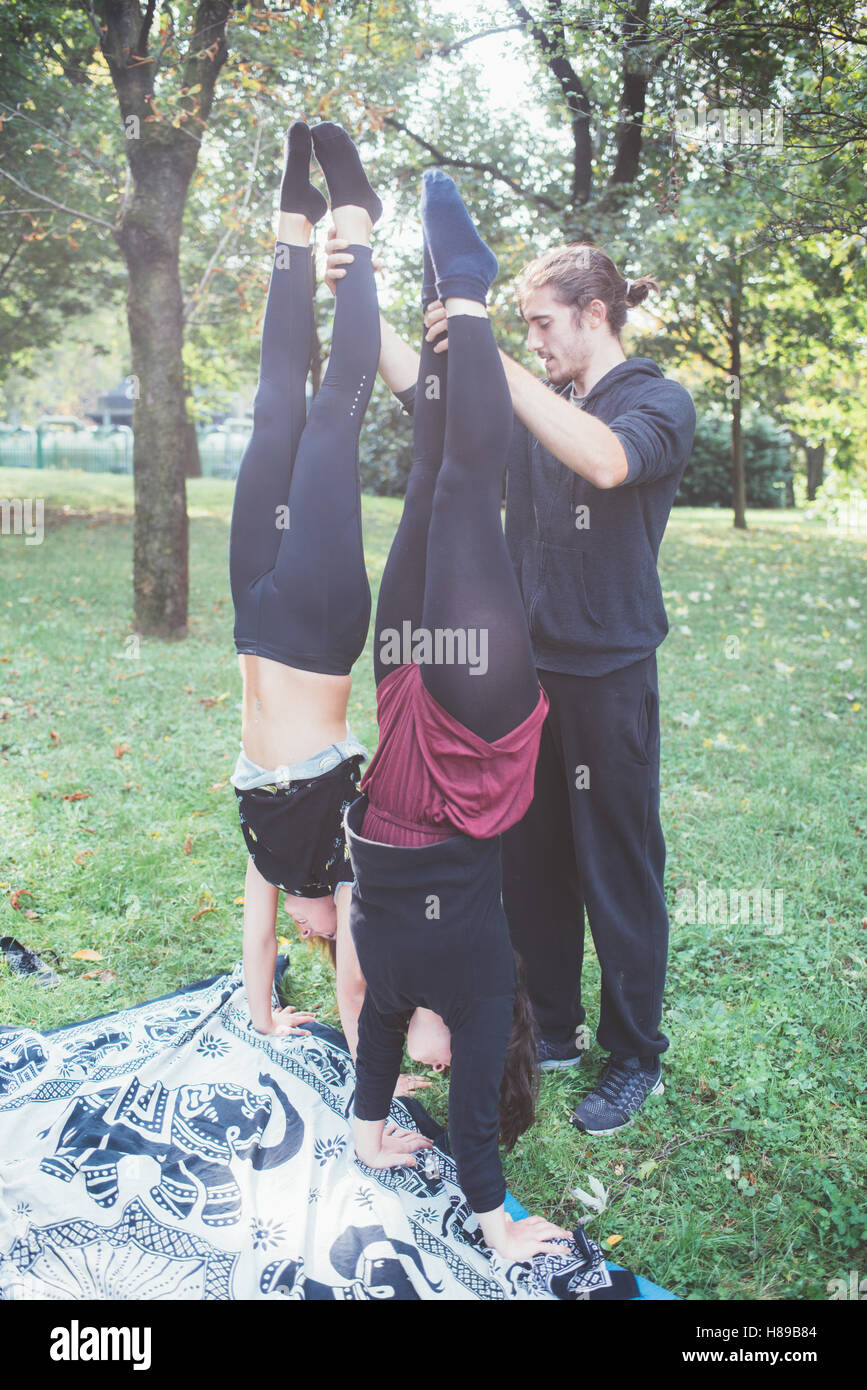 Handstand Outside Man teaching two young girls how to handstand outdoor in a park in ...