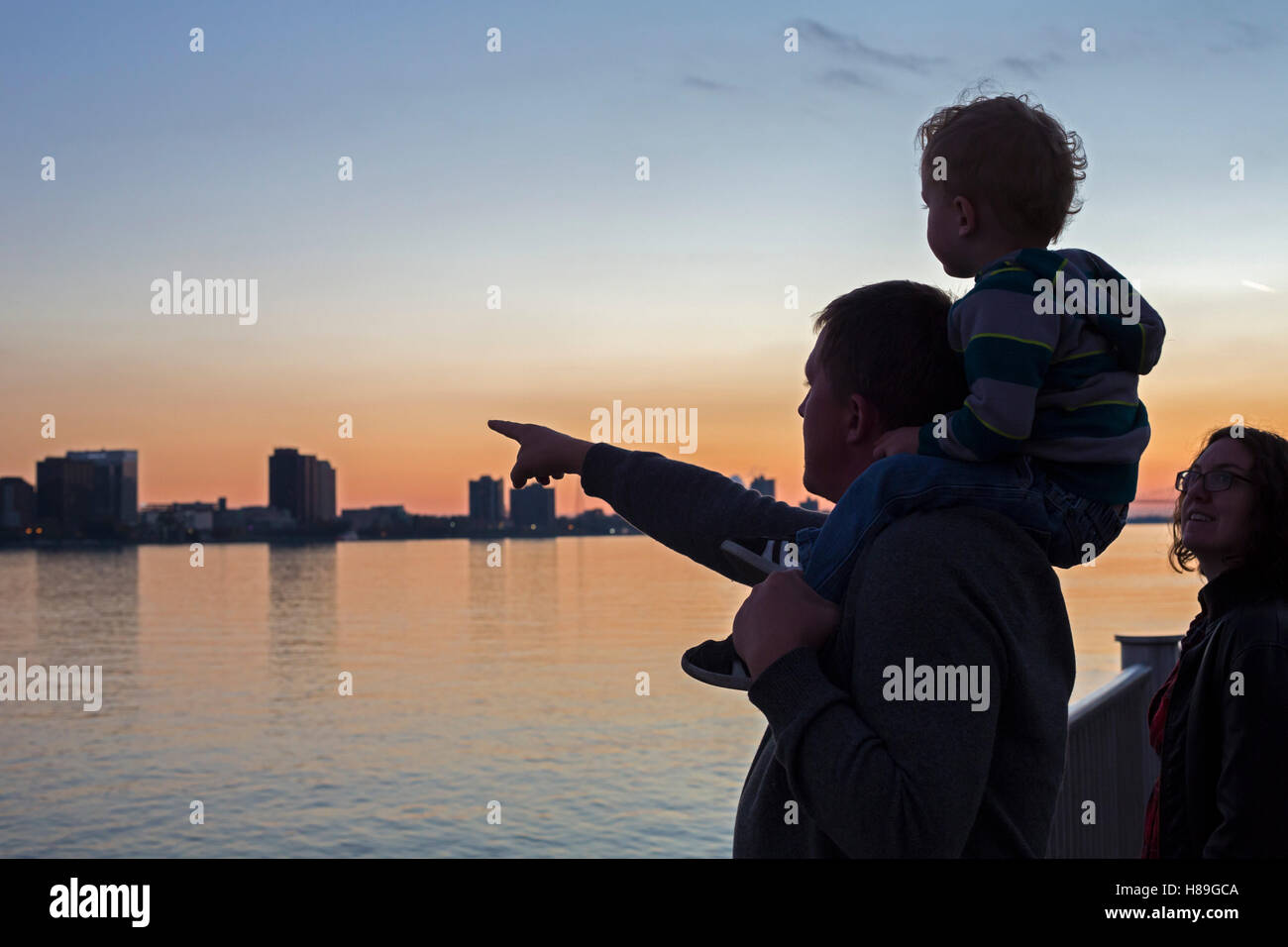 Detroit, Michigan - Dad points across the Detroit River to Canada, with his son and wife. Stock Photo