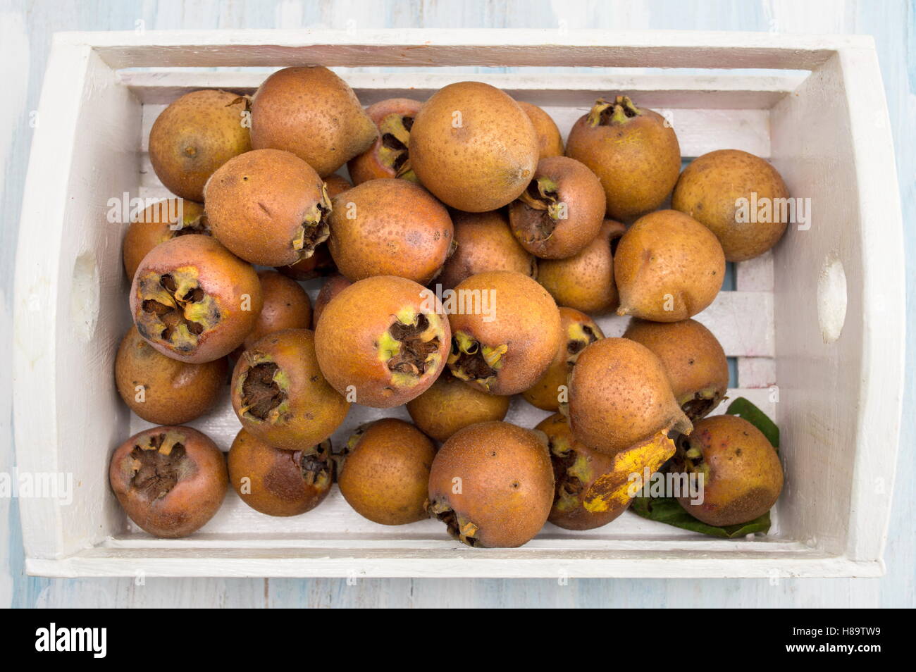Healthy ripe Medlar fruits in a white wooden box Stock Photo