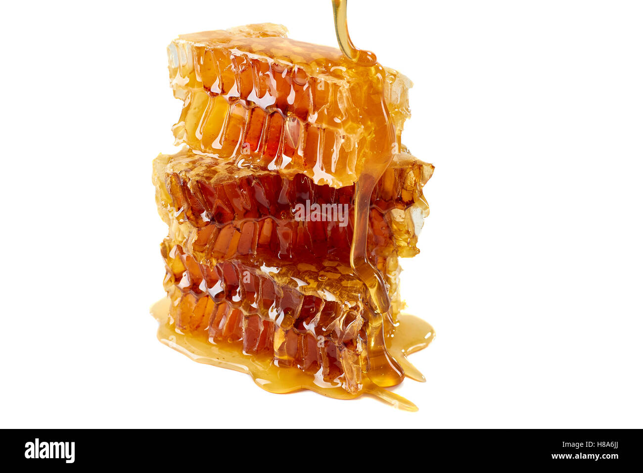 Dripping honey on honeycombs over white background Stock Photo