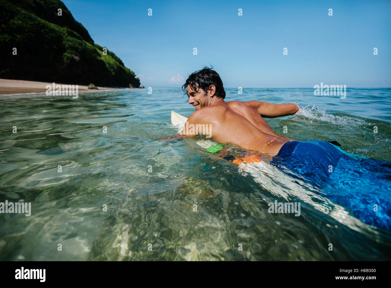 Shot of young man water surfing in sea. Male surfer in the ocean water with surf board. Enjoying holidays. Stock Photo