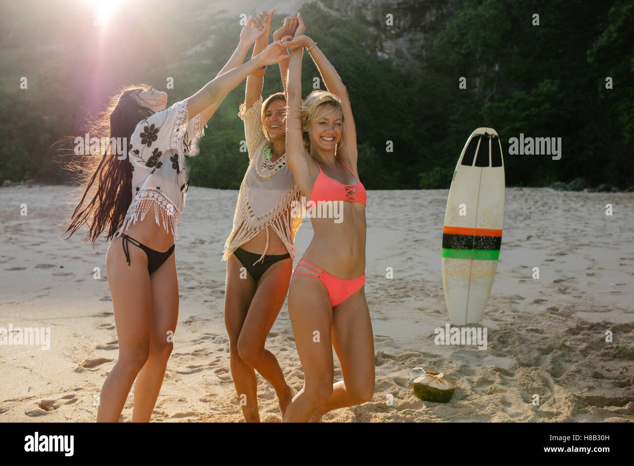 Happy female friends partying on the beach and dancing. Women having fun on the beach party. Stock Photo