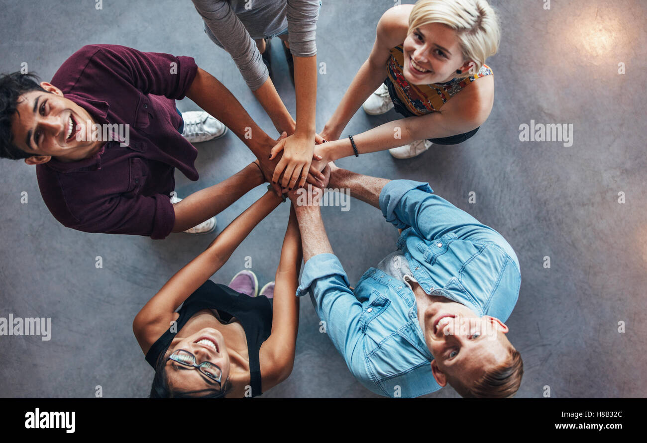 Overhead view of young people standing together looking up at camera with stylish young man gesturing victory sign. Stock Photo