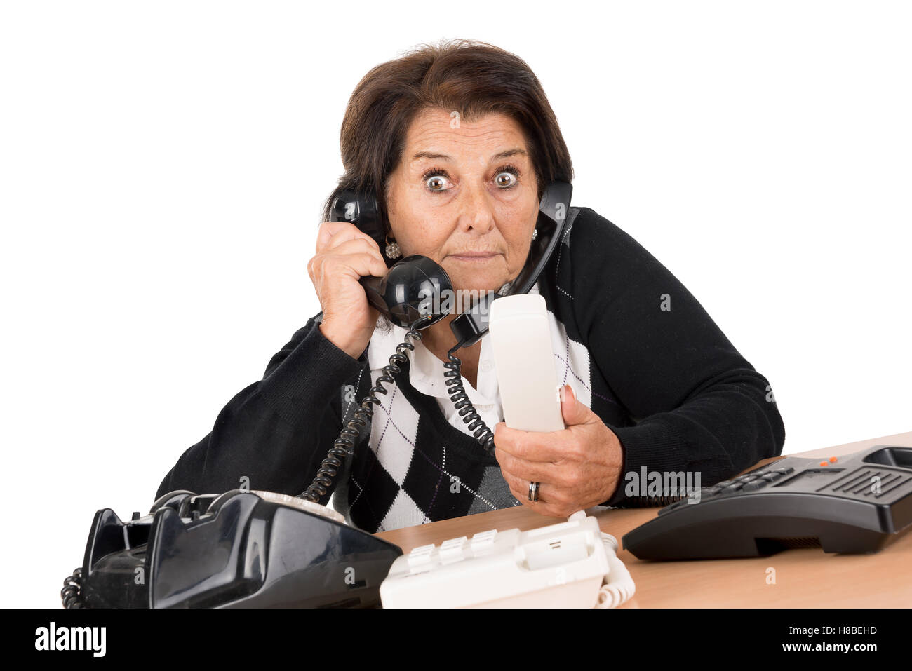 Desperate senior woman with several phones isolated in white Stock Photo