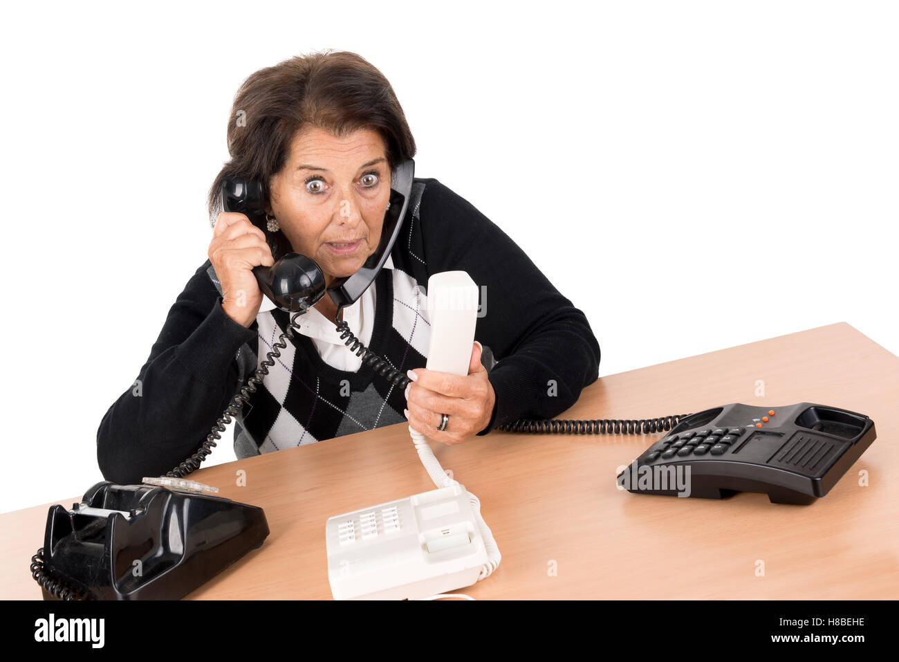 Desperate senior woman with several phones isolated in white Stock Photo