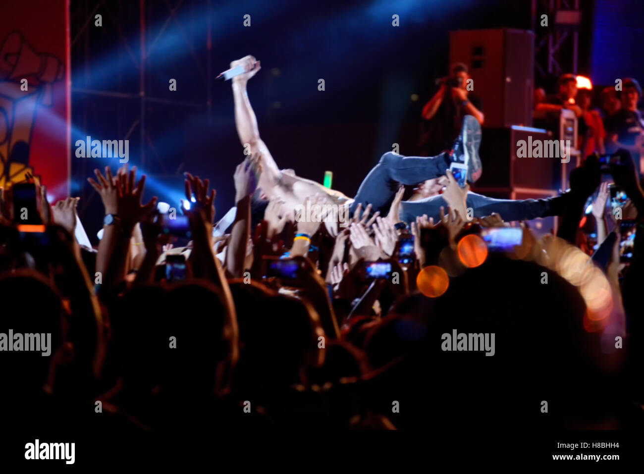 blurred image of singer on top crowd surfing at a music concert Stock Photo