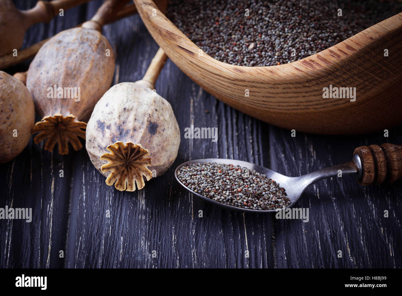 Poppy seeds and heads on wooden background. Selective focus Stock Photo