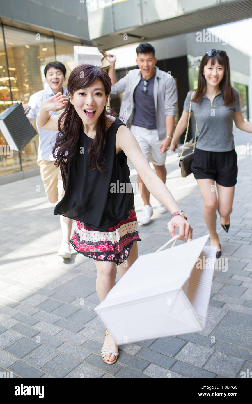 Happy young Chinese friends running with shopping bags Stock Photo - Alamy