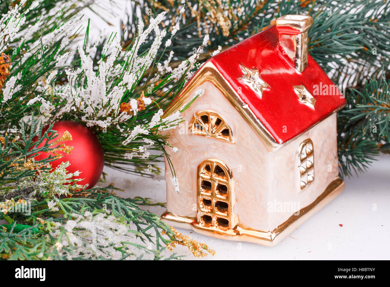 Christmas decoration with red ball, fir-tree branch and toy house. Stock Photo