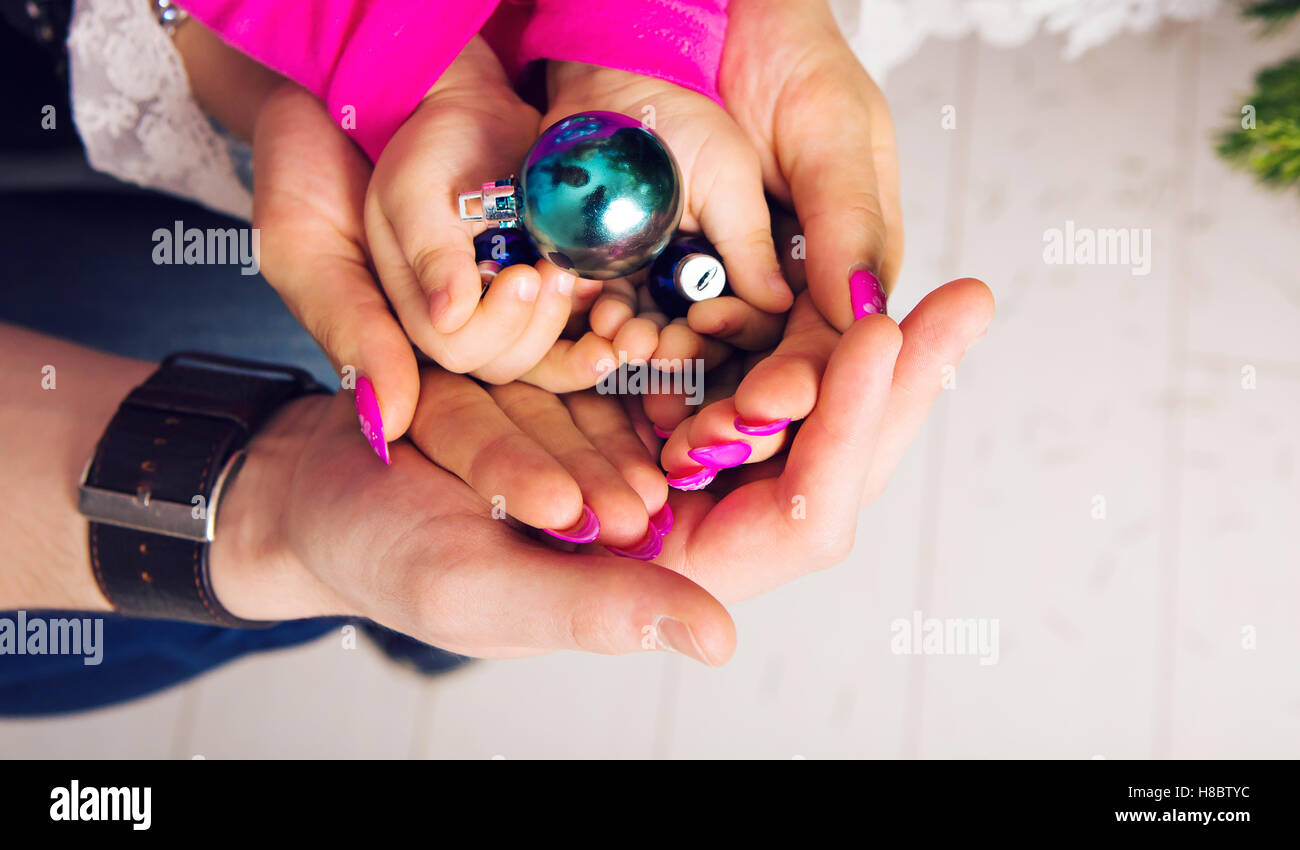 Christmas ball in the hands of the child and father, mother Stock Photo