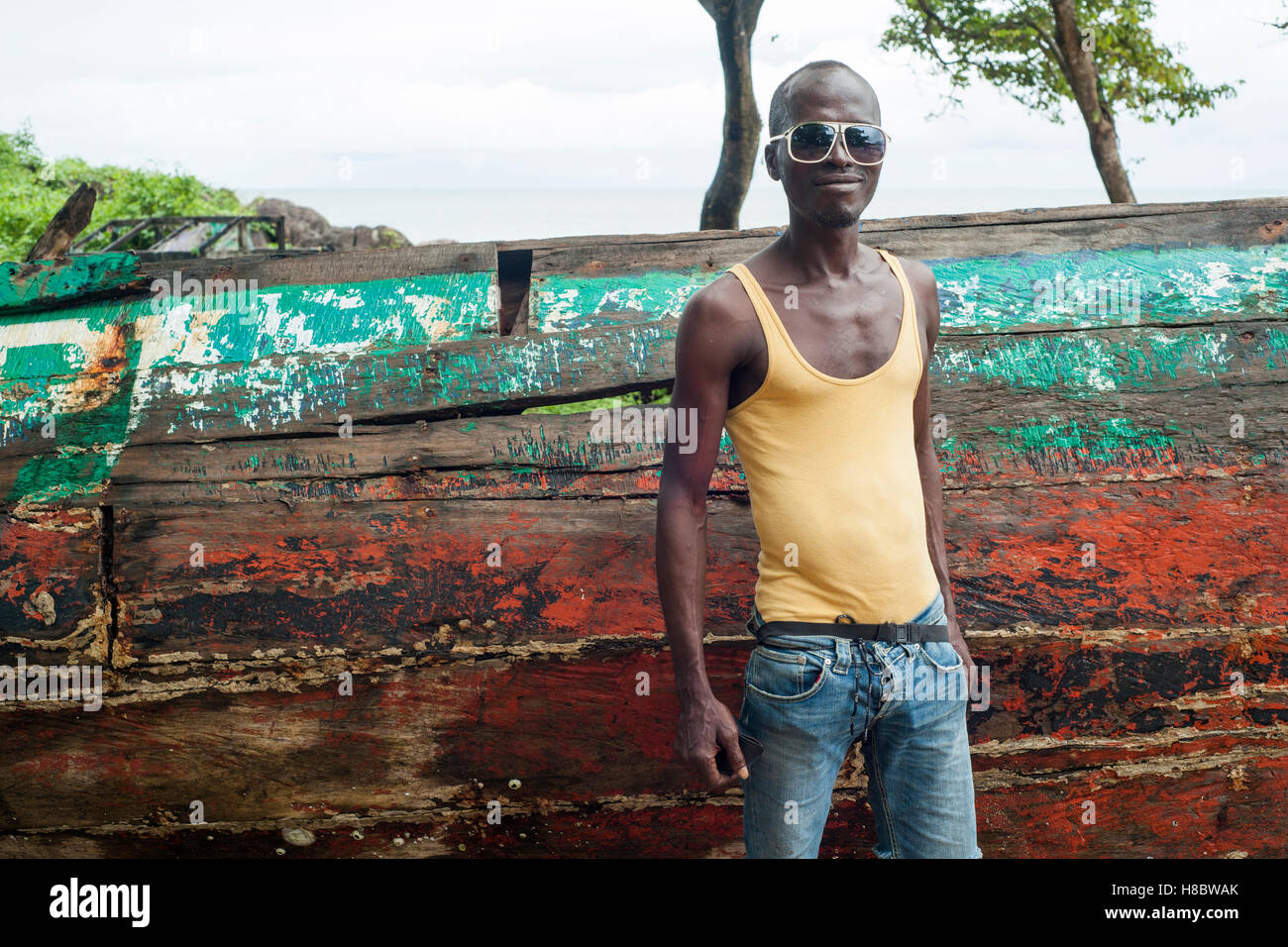 Local fisherman posing in front of a wooden fishing boat in the Kent fishing village, Sierra Leone Stock Photo