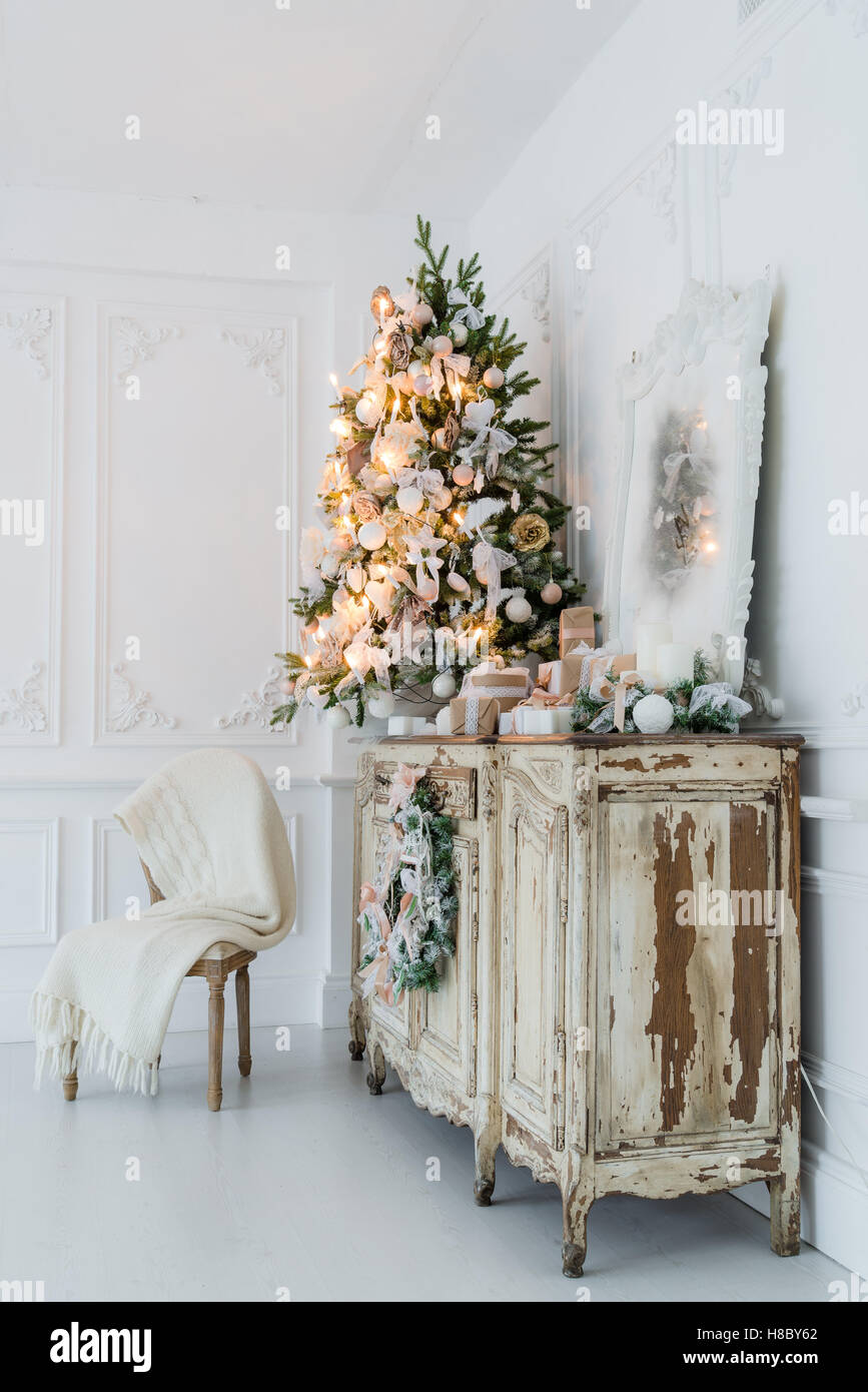 Christmas decoration on ancient vintage old commode chest of drawers. Hand made craft gifts, candels and a tree at background. Selective focus Stock Photo