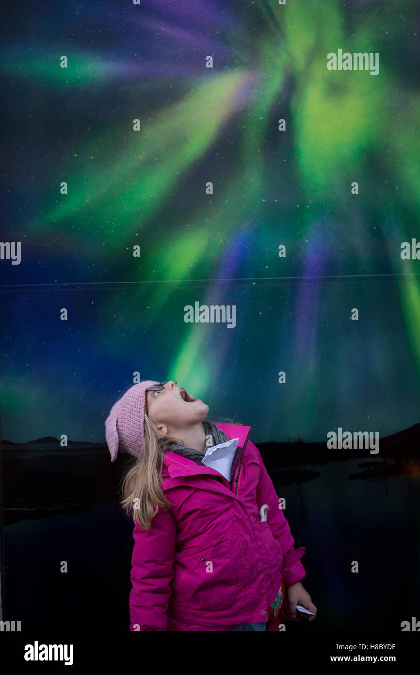 A young girl looks up at a poster of the Northern Lights in Reykjavik, Iceland Stock Photo