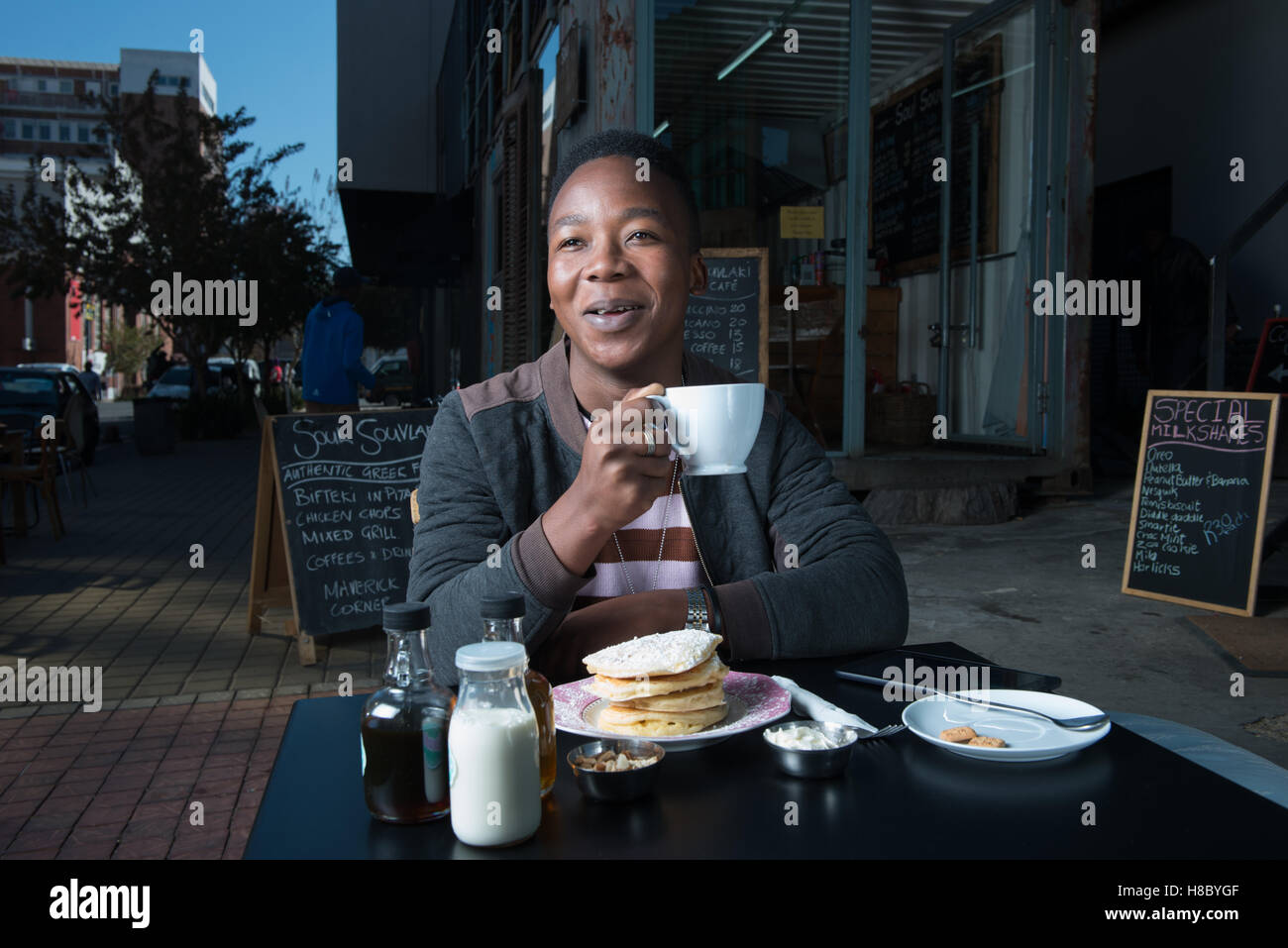 Man drinking coffee and eating flapjacks at a coffee shop in Johannesburg Stock Photo