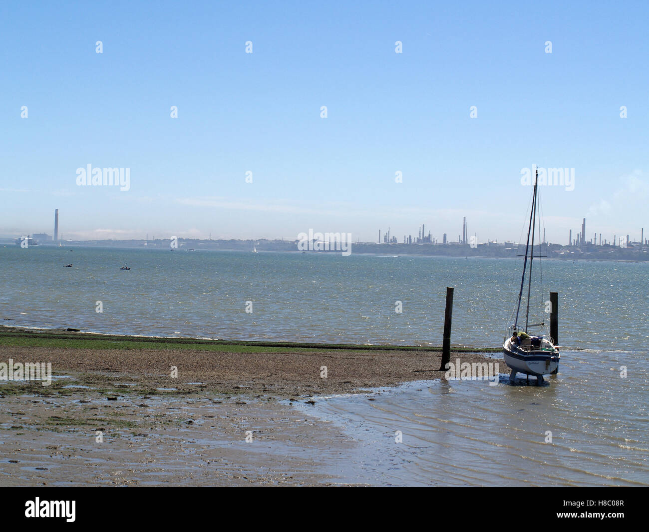 Man working on maintaining yacht at Weston Shore, Woolston, Southampton, Hampshire UK with Fawley Refinery in distance Stock Photo