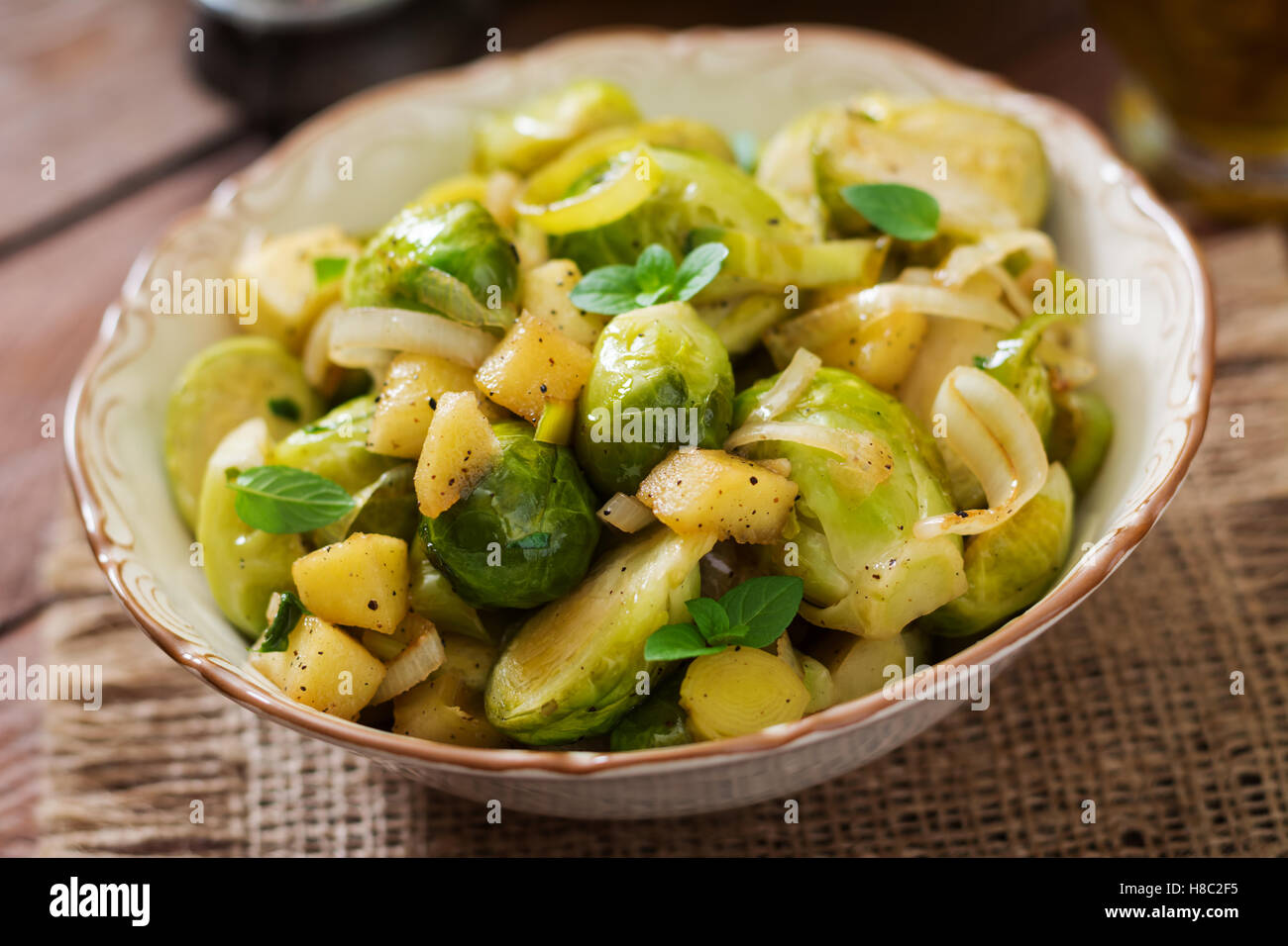 Stewed Brussels cabbage sprouts, apples and leeks in bowl. Dietary menu. Stock Photo