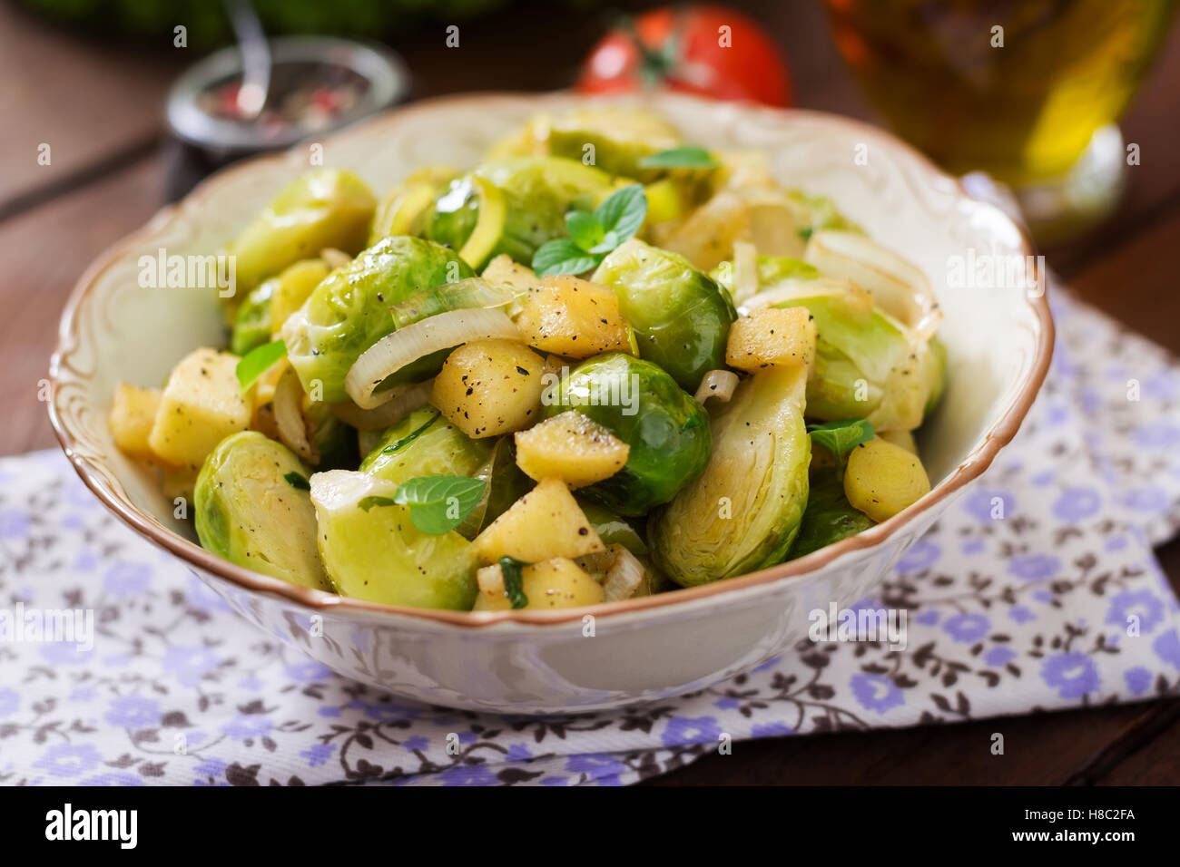 Stewed Brussels cabbage sprouts, apples and leeks in bowl. Dietary menu. Stock Photo
