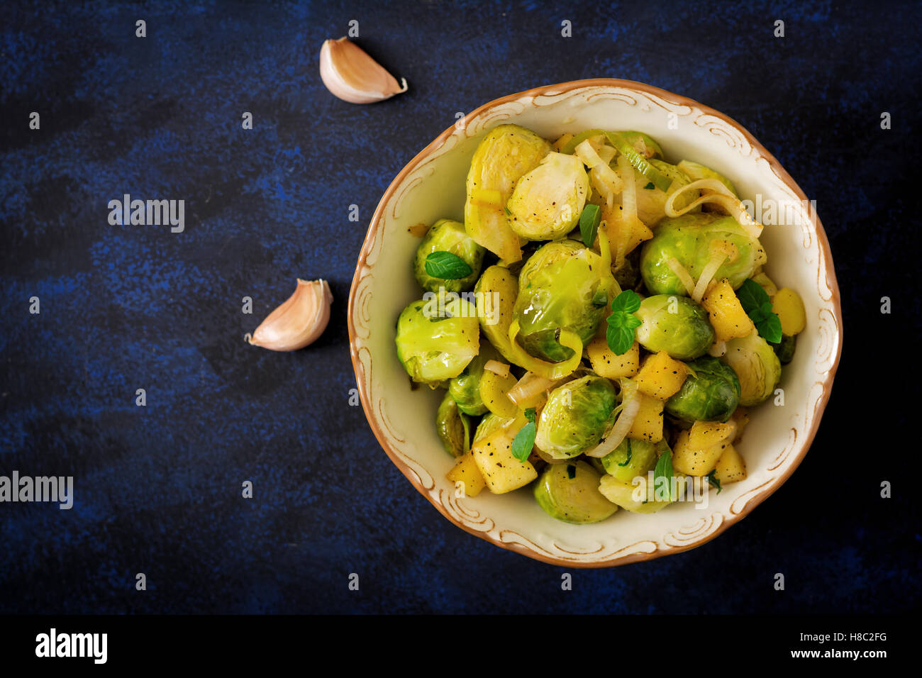 Stewed Brussels cabbage sprouts, apples and leeks in bowl. Dietary menu. Top view Stock Photo