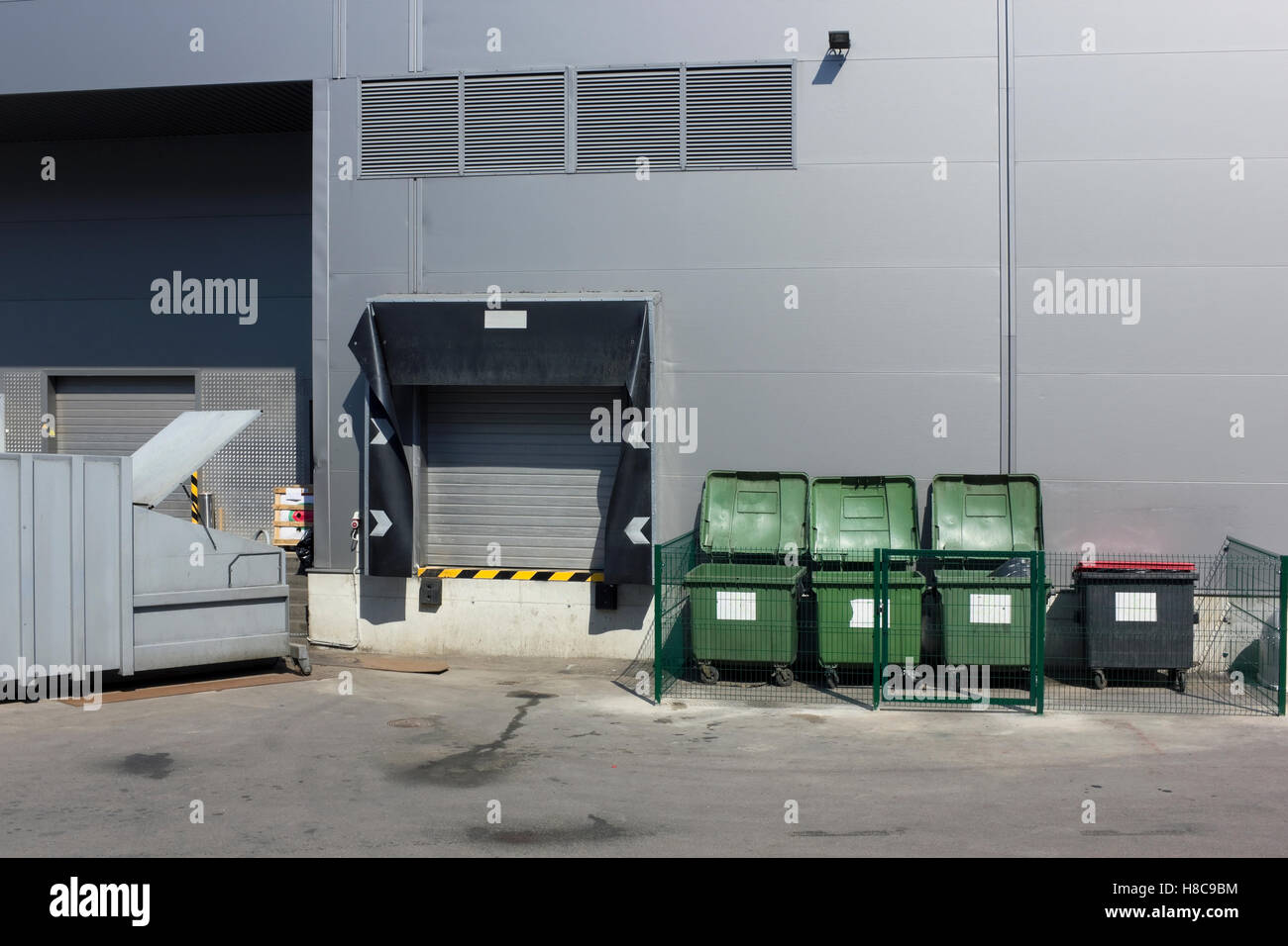 Back side of modern European grocery store. Empty green plastic trash