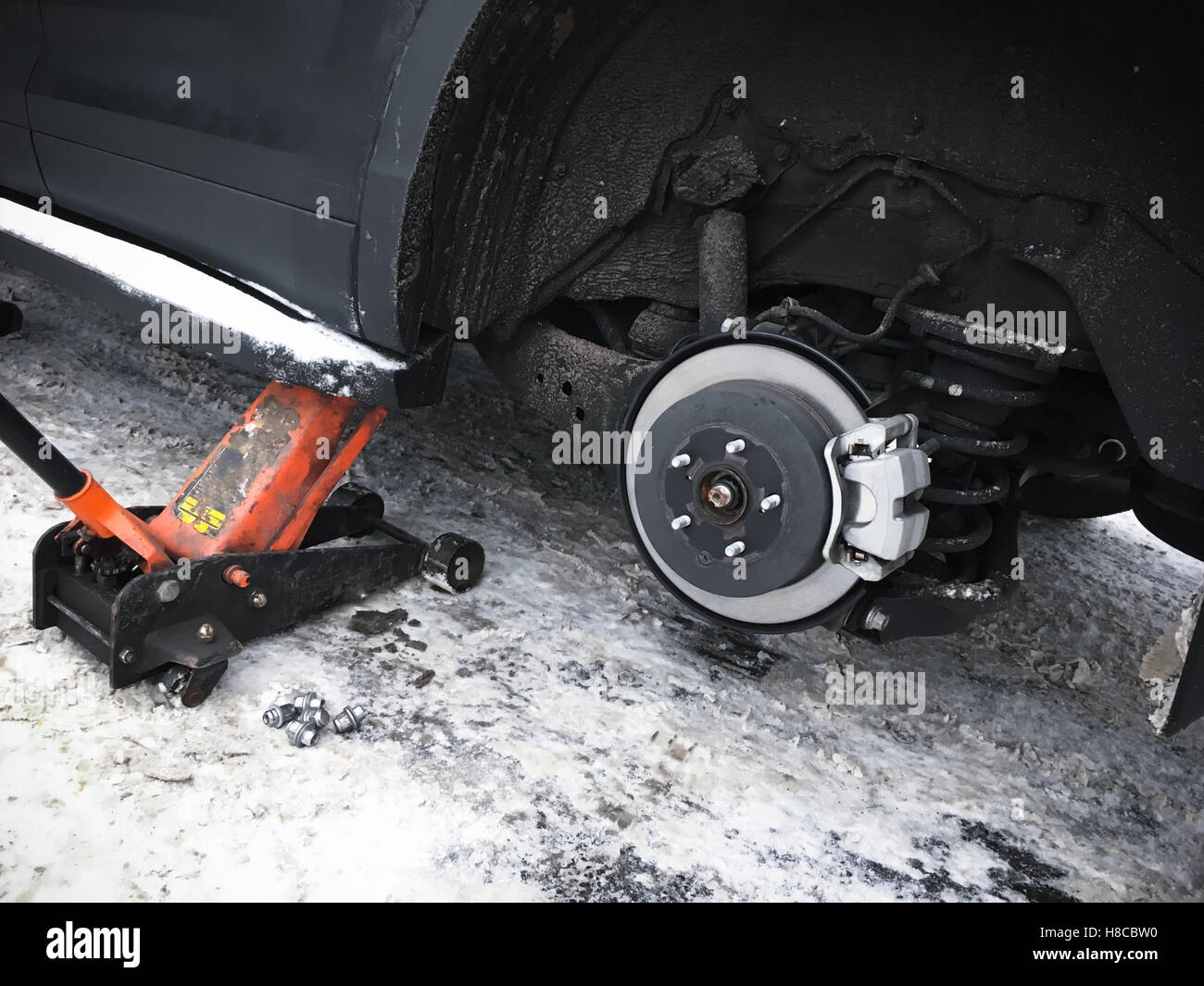Wheel replacement on new black SUV car, jack holds the body in the raised position Stock Photo