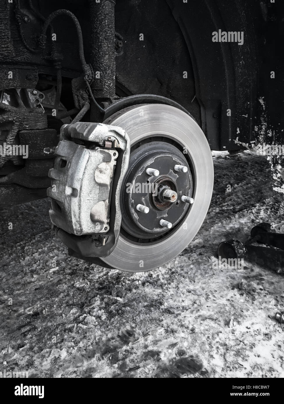 Replacing wheel on modern car, black and white photo of rotor disk with brake, selective focus
