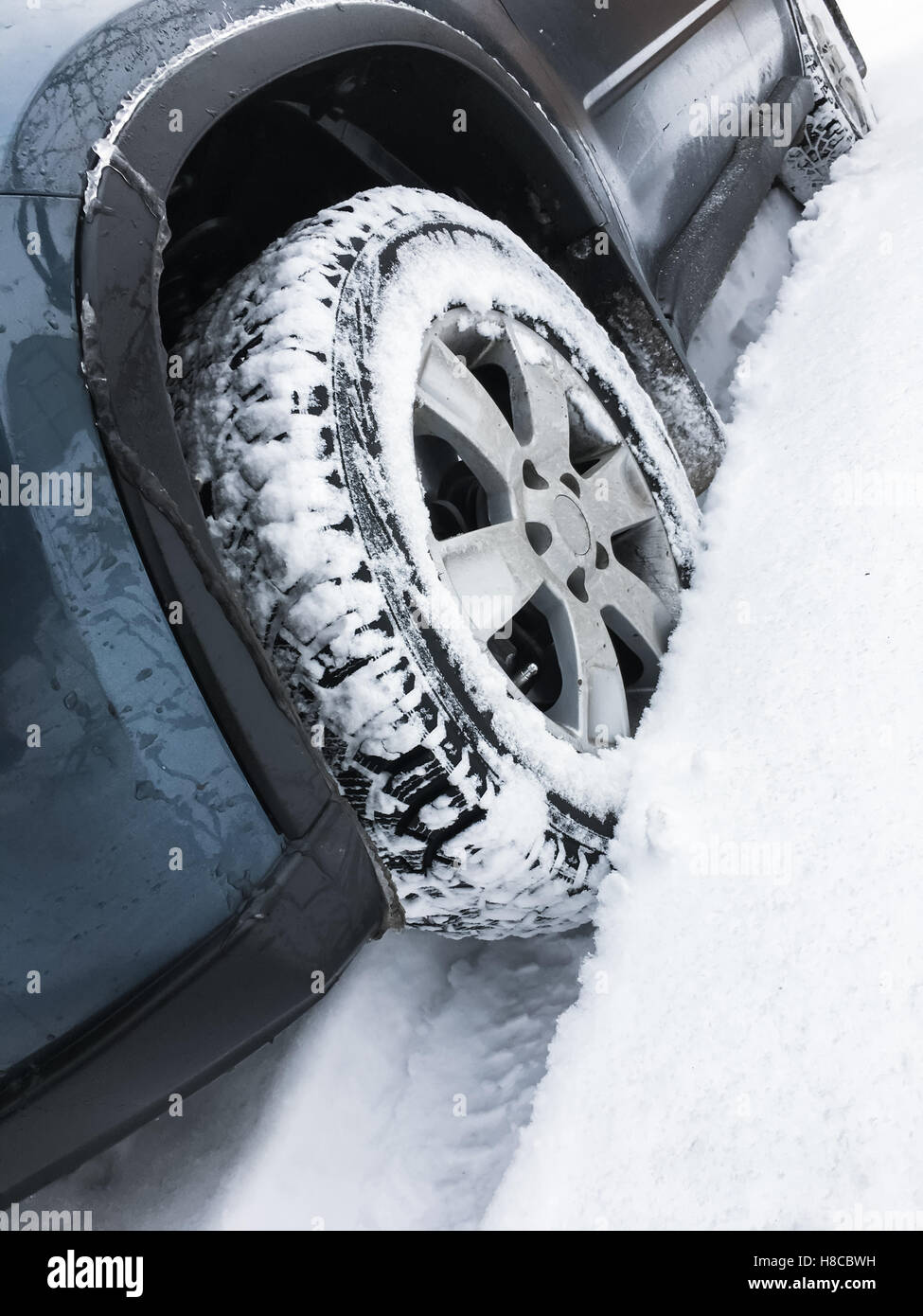 Modern blue car fragment, wheel with studded tire standing on winter
