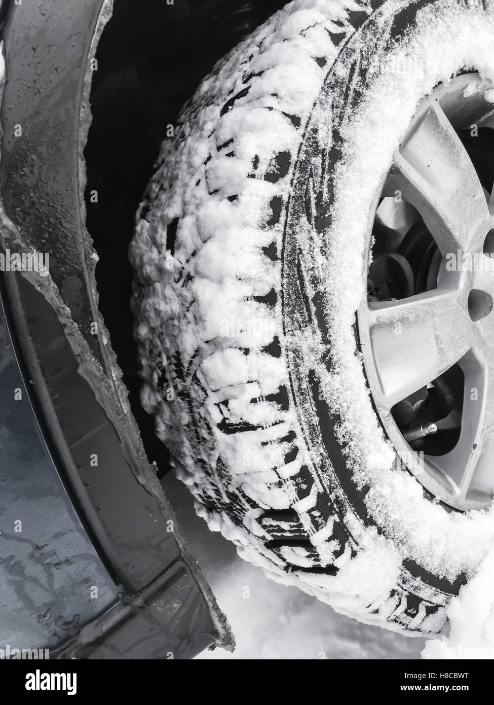 Car wheel with studded tire standing on winter road with deep snow