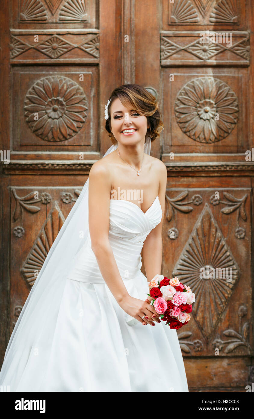 Smiling bride standing near wooden door Stock Photo - Alamy