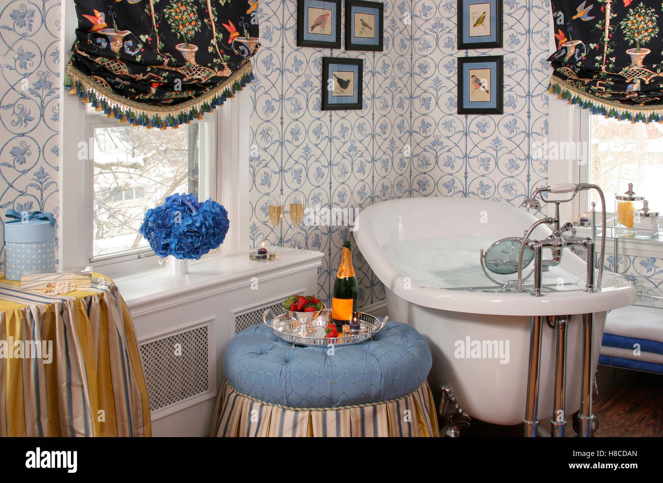 Bathroom with patterned wallpaper and framed pictures above a free