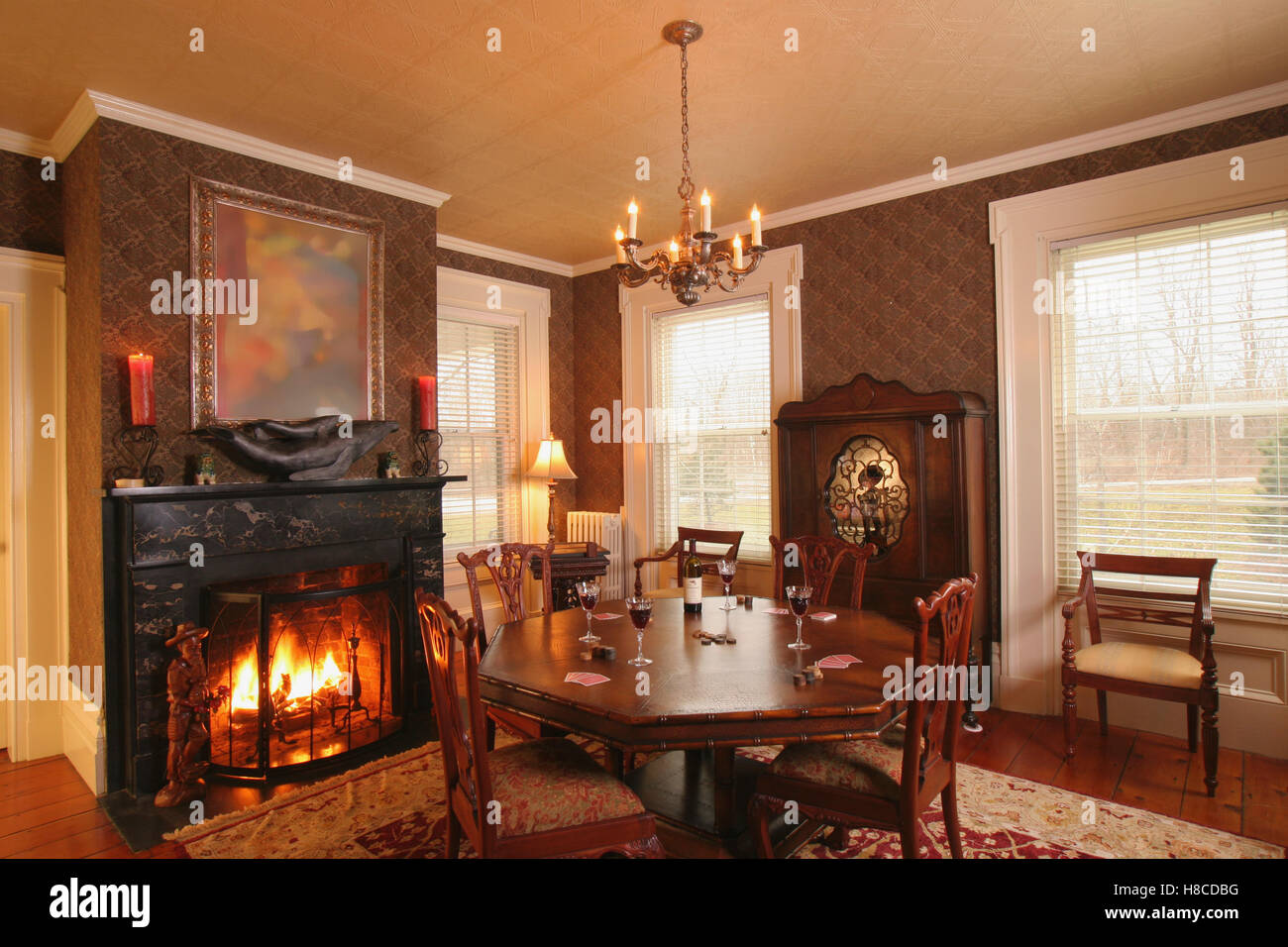 Wooden table and chairs in front of fireplace in lit fire Stock Photo
